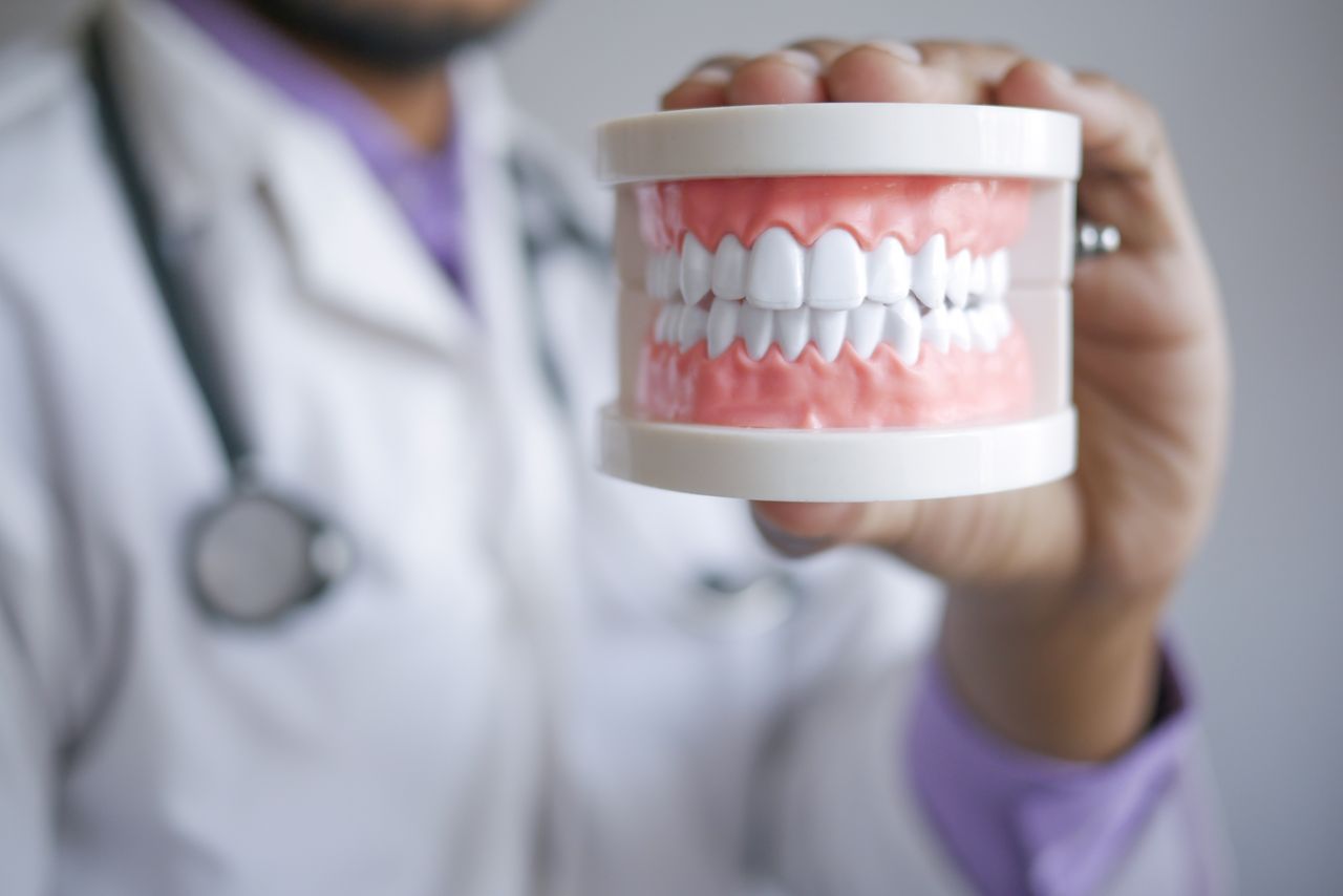 Dentist showing teeth model to explain what causes sensitive teeth